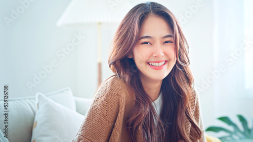 Confident smiling young adult asian woman looking at camera while sitting at home, Happy beautiful lady pretty face dental smile posing alone indoors. Free Download Confident smiling young adult asian woman looking at camera while sitting at home, Happy beautiful lady pretty face dental smile posing alone indoors. - GFXLoad