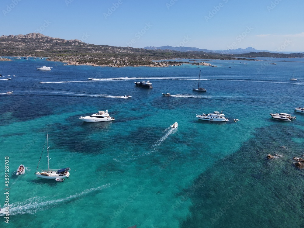 Obraz premium Aerial view of La Maddalena Island, Isola Giardinelli with the drone view of Caprera Island in Sardegna, Italy. Birds eye view of crystalline and turquoise water in north Sardinia, luxury yacht, boat.