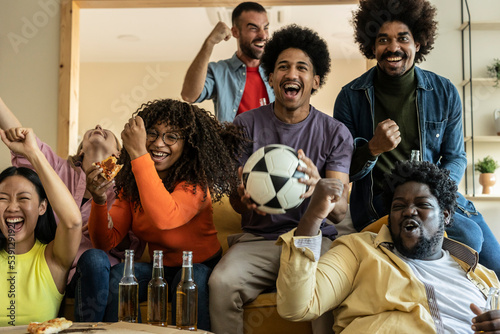 Group of friends having fun at home,watching game and enjoying together.