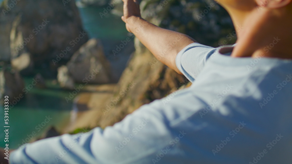 Hands namaste yoga position at ocean cliff closeup. Unrecognized man meditating