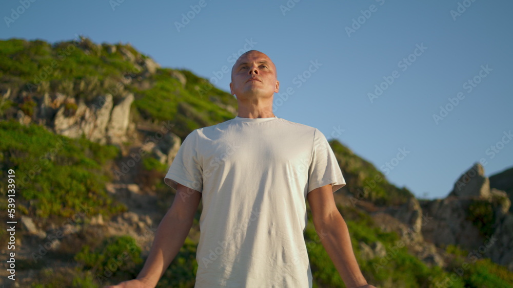 Athlete breathing yoga position at green mountain. Focused man making namaste