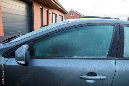 A portrait of the side of a car which completely frozen. The driver side window is frozen shut. The ice first needs to melt or be removed before the driver can safely start the journey.