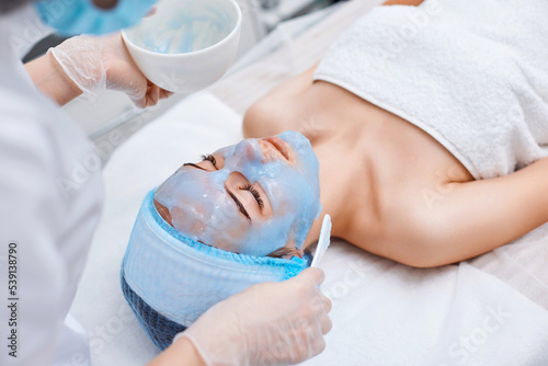 beautician applies the mask to the face of beautiful woman