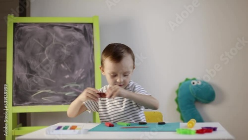 a little boy sculpts from plasticine on the table. Tactile activity, fine motor skills.