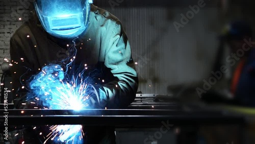 worker a welder welds iron and sparks fly in all directions