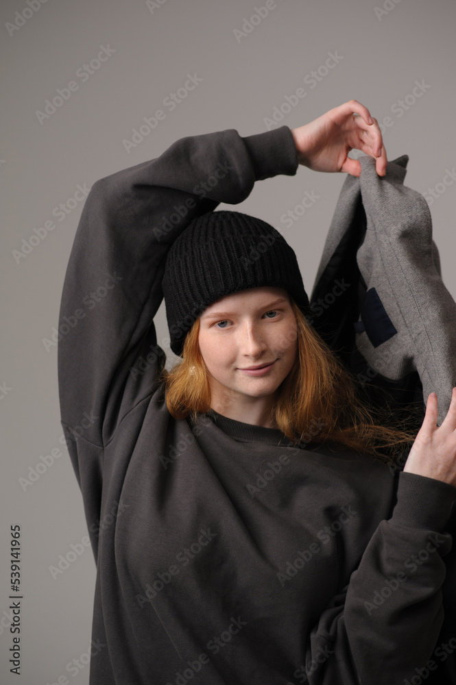 young girl model in black cap and grey jackett isolated on grey background. Product photo mockup for fashion brands and marketplaces.