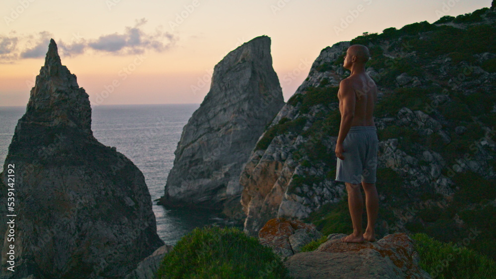 Zen man relaxing sunset at beautiful ocean cliff edge. Focused yogi breathing