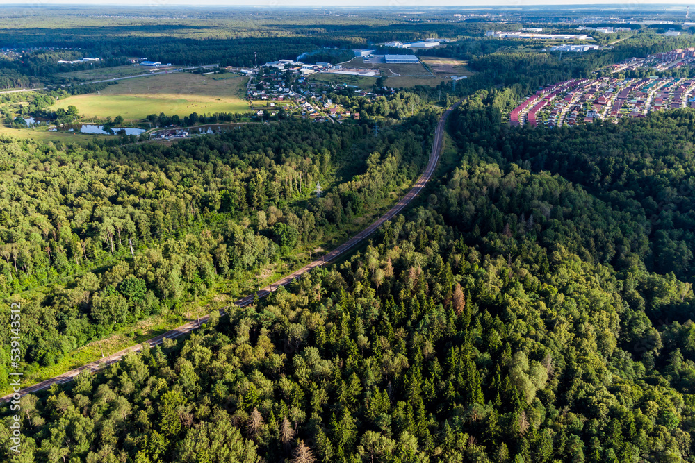 Aerial view of the railway passing through the forest area and small settlements