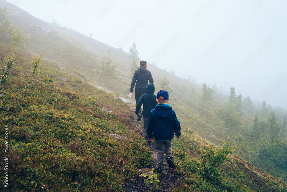 Hiker with children on footpath  in the fog. Norway