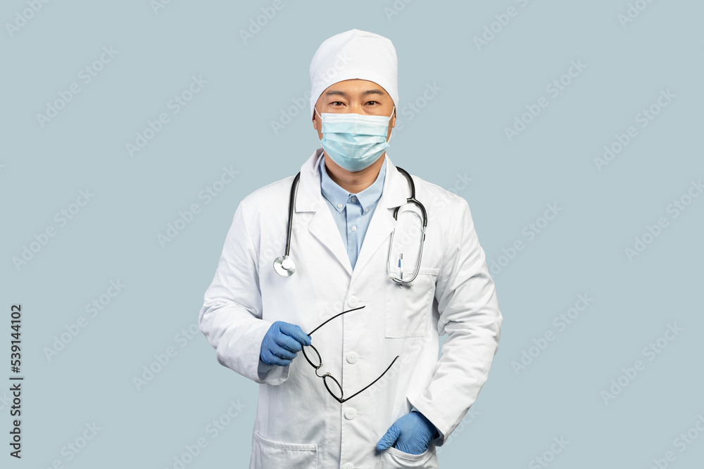 Confident mature korean man doctor in white coat, protective gloves, mask takes off glasses Confident mature korean man doctor in white coat, protective gloves, mask takes off glasses