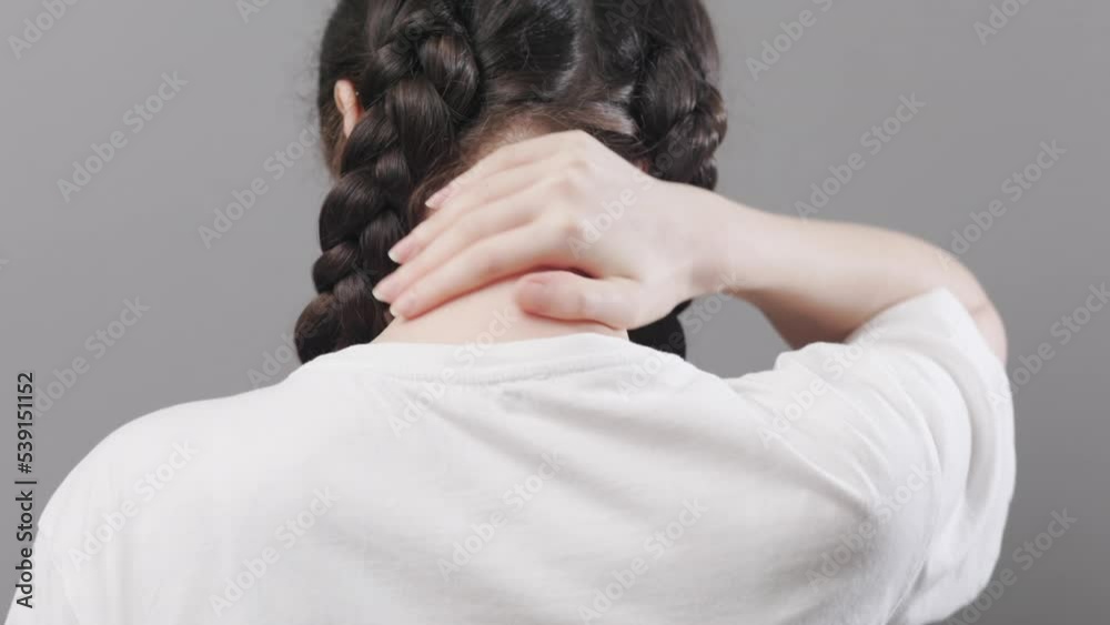 Arthritis and chondrosis. Woman with piggy tails massages neck with her