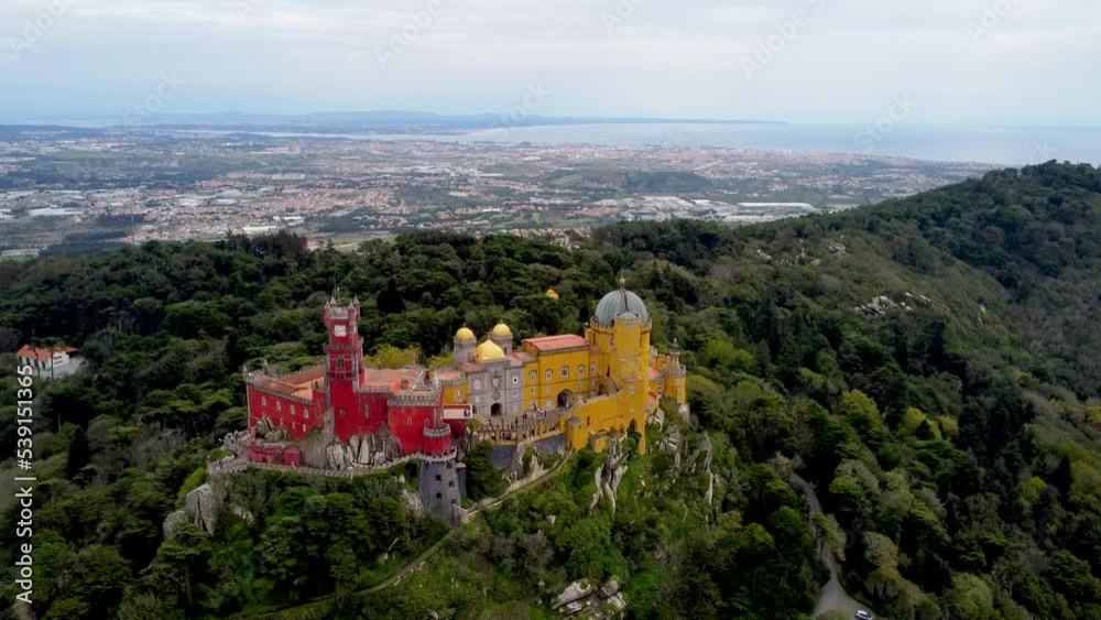Cinematic aerial perspective of Pena Palace, Sintra, Portugal. Situated in top of a hill in the Sintra Mountains. In background Cintra city. Drone ascending and tilt down. Cinematic aerial perspective of Pena Palace, Sintra, Portugal. Situated in top of a hill in the Sintra Mountains. In background Cintra city. Drone ascending and tilt down.
