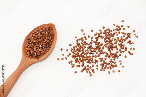 small grains of brown natural buckwheat in a wooden spoon