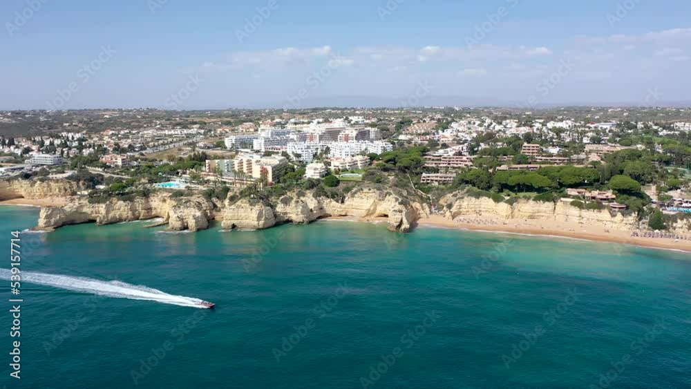 Drone point of view of beautiful Portuguese city Carvoeiro. Situated in Lagoa, Algarve, South of Portugal, is a travel destination. Typically Portuguese landscape, boat passing. Drone backward. Drone point of view of beautiful Portuguese city Carvoeiro. Situated in Lagoa, Algarve, South of Portugal, is a travel destination. Typically Portuguese landscape, boat passing. Drone backward.