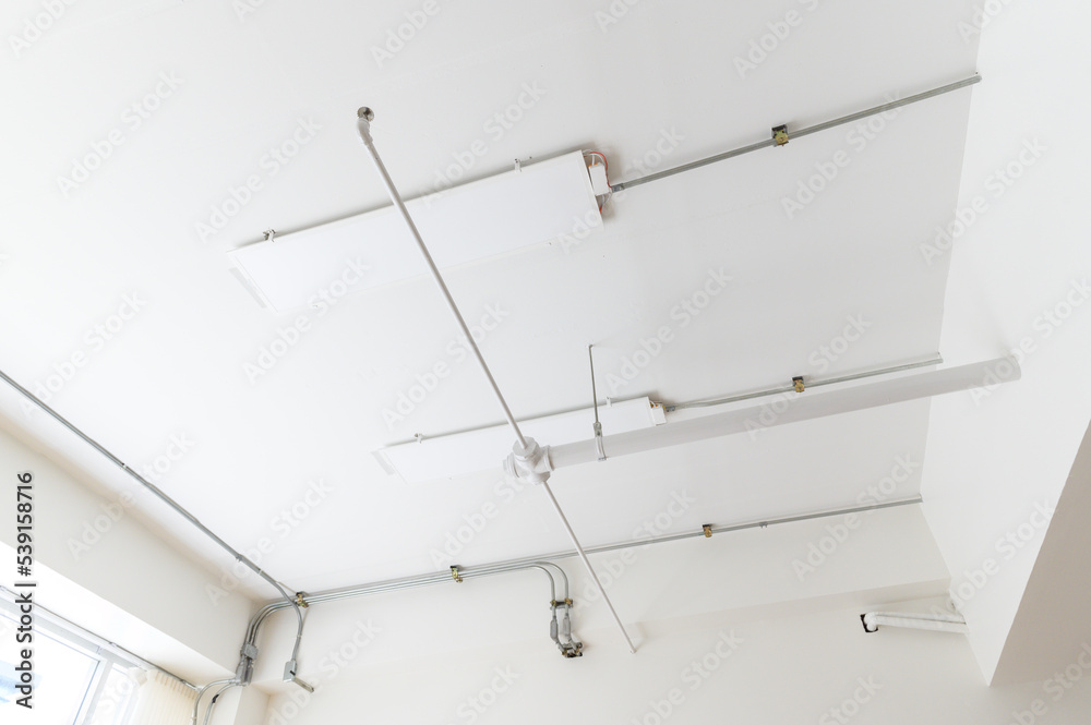 Electrical wires and pipes on house concrete ceiling background, plastic hoses with cables in empty room. Lines of pvc tubes, conduit after professional work. Renovation of home or factory interior Electrical wires and pipes on house concrete ceiling background, plastic hoses with cables in empty room. Lines of pvc tubes, conduit after professional work. Renovation of home or factory interior