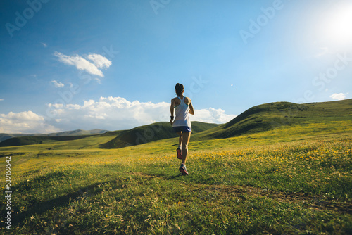 Young fitness woman trail runner running on high altitude grassland
