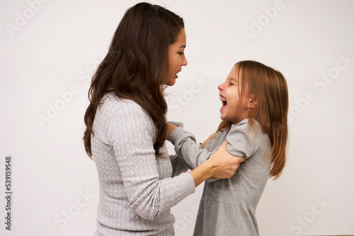 Angry mother beat up sad daughter on white background