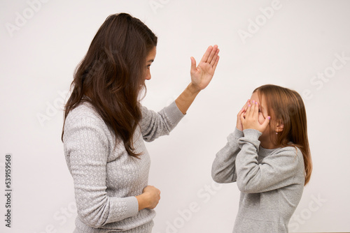 Angry mother beat up sad daughter on white background