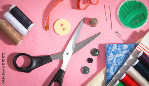 Sewing tools on the pink paper background.
