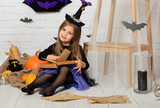 Portrait of an angry little girl in a witch costume. Halloween. Little halloween witch with black hat.Boo
