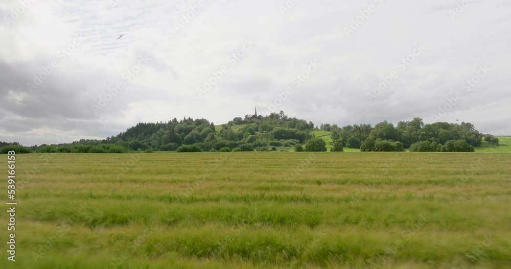 Drone flying over long grass in a field with hill backdrop in Europe Drone flying over long grass in a field with hill backdrop in Europe