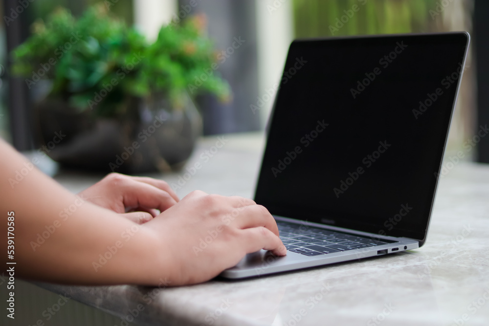 A man works in front of a laptop on a white marble table in a public space outside his home. A man works in front of a laptop on a white marble table in a public space outside his home.
