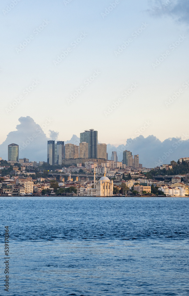 Fototapeta premium Skyscrapers of istanbul behind Ortaköy Camii mosque and city behind, aerial view of the Bosporous in Istanbul
