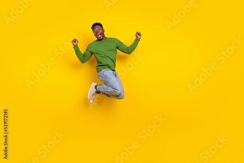 Full length body size view of attractive ecstatic guy jumping having fun attainment isolated over shine yellow color background