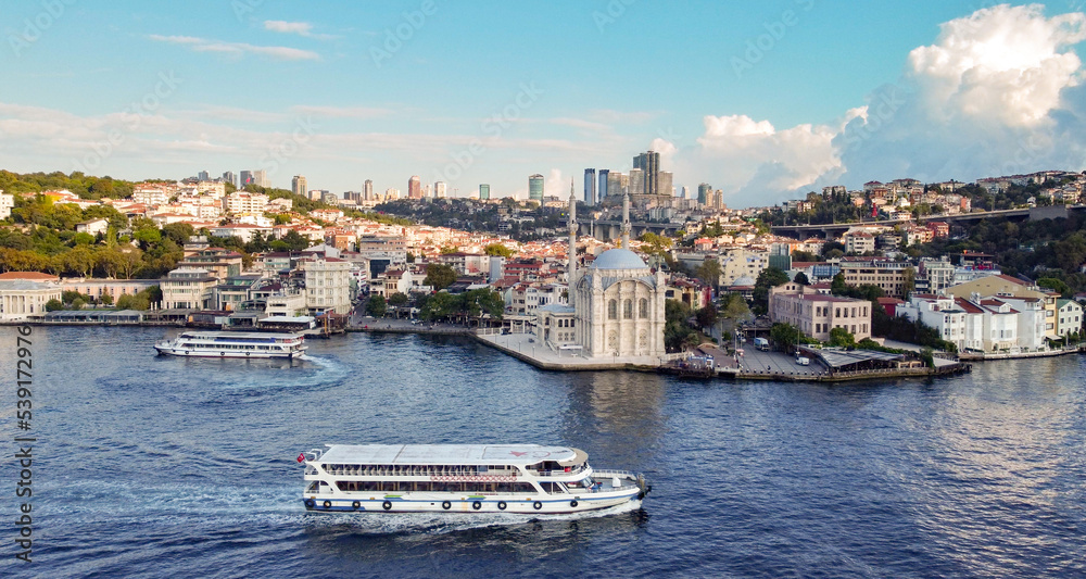 Aerial drone view of Ortaköy mosque on the Bosporous in Istanbul with ferry boat cruising in front