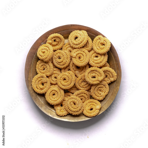 Crunchy fried homemade Chakli,chakkuli, murukku in a wooden traditional plate on white background top view photo