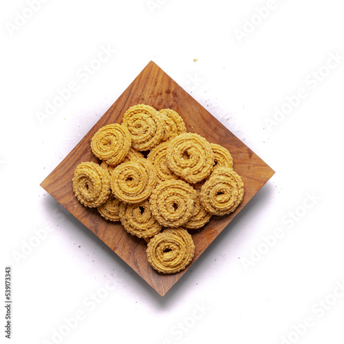 Crunchy fried homemade Chakli,chakkuli, murukku in a wooden traditional plate on white background top view photo
