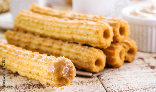 Fototapeta Naklejka Na Ścianę i Meble -  Churros, typical sweet from Brazil and America, fried and stuffed with sweet milk, covered in sugar, tradition in popular festivals