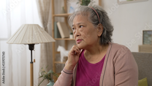 depressed asian old lady feeling loneliness and burying face in hands while worrying about problems in the living room at home.