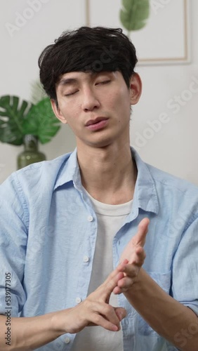 Vertical Screen: webcam view asian male creative worker working from home is expressing ideas to client with hand gestures in a virtual meeting via video call in the living room