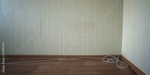 Fototapeta TV cable is stretched along wall and lies near wooden plinth on floor