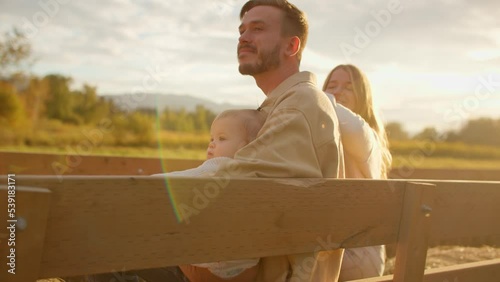 Young family enjoying farmfield views on tractor ride, golden hour photo