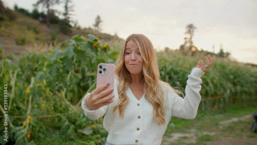 Female content creator takes selfie video at sunflower field, farm Female content creator takes selfie video at sunflower field, farm