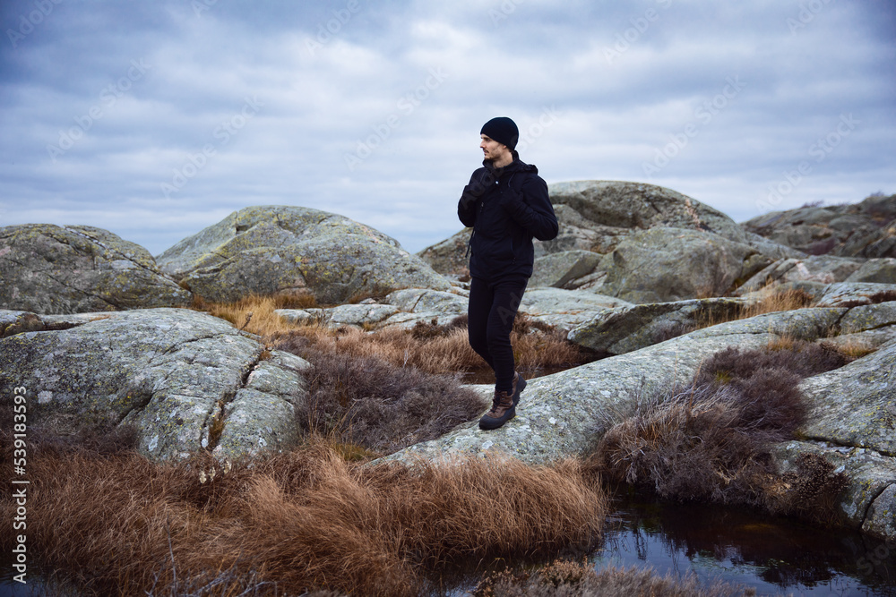 An man with a backpack walking on rocks on a cloudy day. An man with a backpack walking on rocks on a cloudy day.