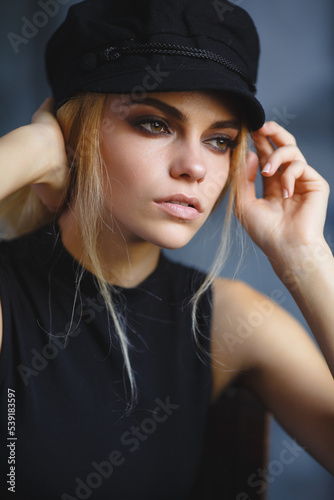 Stylish portrait of a young attractive girl with a European appearance. A girl with big eyes in a black fashion hat. A large portrait