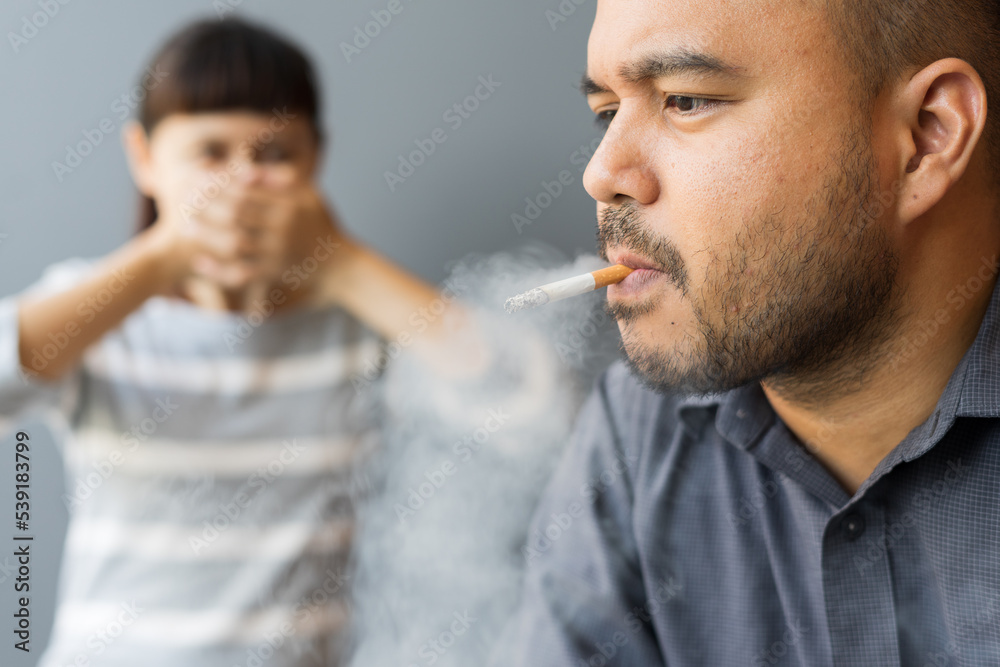 Husband smoking cigarette and wife choking of smoke. Man smoking