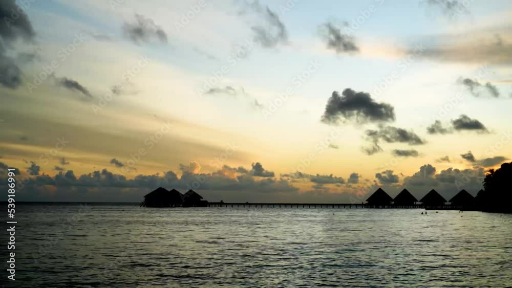 Sunset timelapse with water villas in the Maldives in the background. The clouds are moving. Honeymoon in the Maldives. Sunset timelapse with water villas in the Maldives in the background. The clouds are moving. Honeymoon in the Maldives.