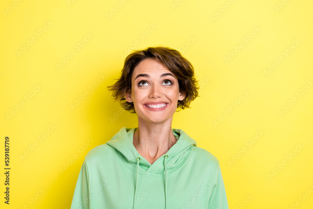 Close up photo of overjoyed excited lady wear green clothes interested look up empty space low price isolated on yellow color background Close up photo of overjoyed excited lady wear green clothes interested look up empty space low price isolated on yellow color background