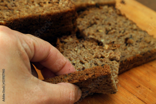A woman breaks off a piece of whole grain bread. Defocus. Healthy food concept.