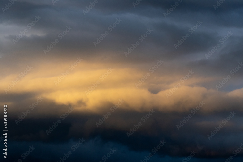 Dark cloud before raining storm and have the orange cloud that reflect light from sunset as background