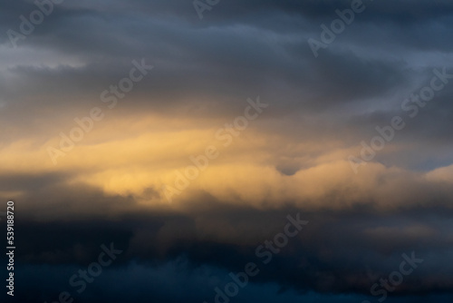 Dark cloud before raining storm and have the orange cloud that reflect light from sunset as background