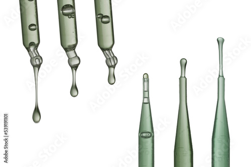 Set of various glass pipettes with dripping gray liquids against white background in modern scientific lab photo