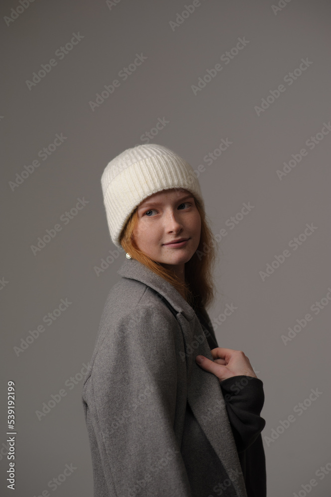 young girl model in white cap and gray coat isolated on grey background. Product photo mockup for fashion brands and marketplaces.