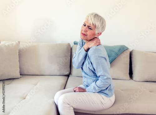 Pain in the shoulder. Upper arm pain, people with body-muscles problem, healthcare and medicine concept. Attractive mature woman sitting on the bed and holding painful shoulder with another hand.