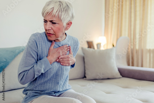 Upset stressed mature middle aged woman feeling pain ache touching chest having heart attack. Sad worried senior older lady suffers from heartache at home, infarction or female heart disease concept. © Jelena Stanojkovic