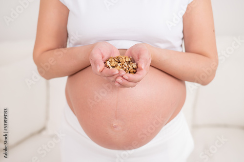 Pregnant woman holding a handful of walnuts. 
